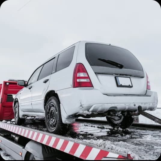 Car on tow truck covered in snow