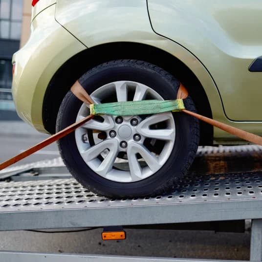 Car secured with straps inside a transportation truck