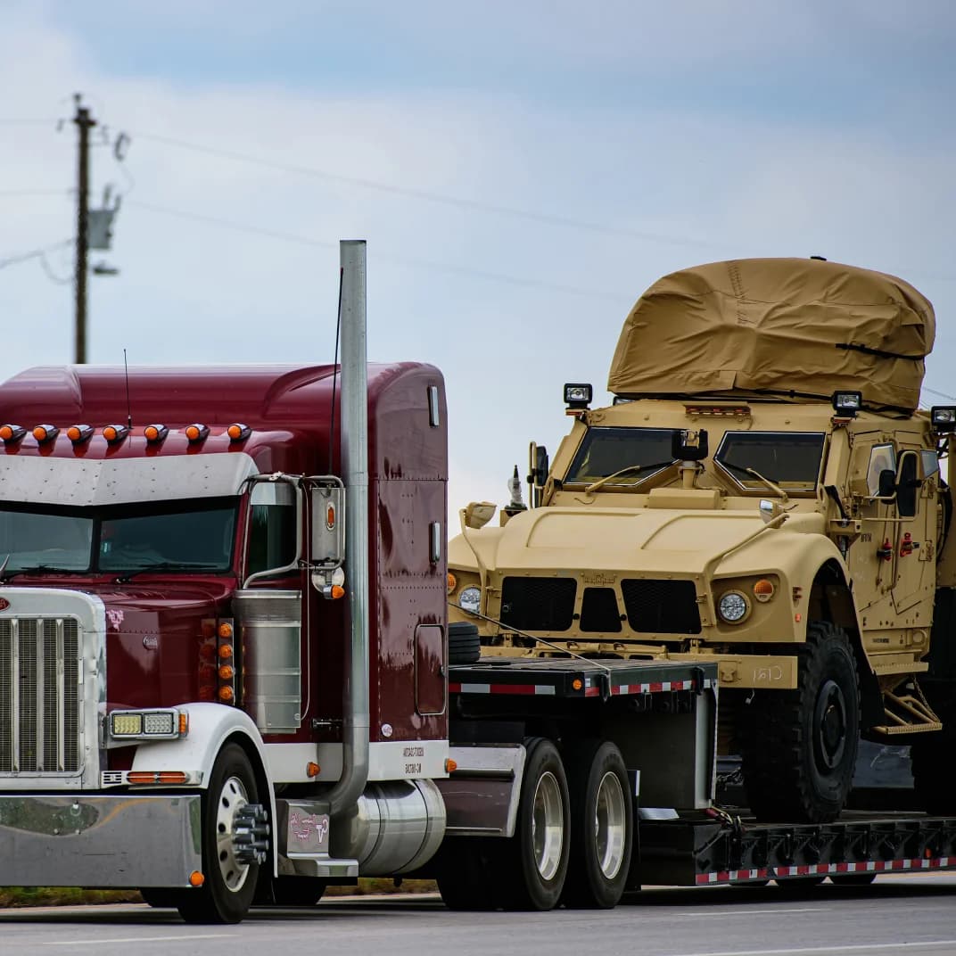 Military car being transported by truck