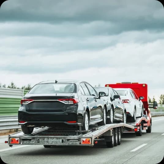 Three cars on a hauler on the road