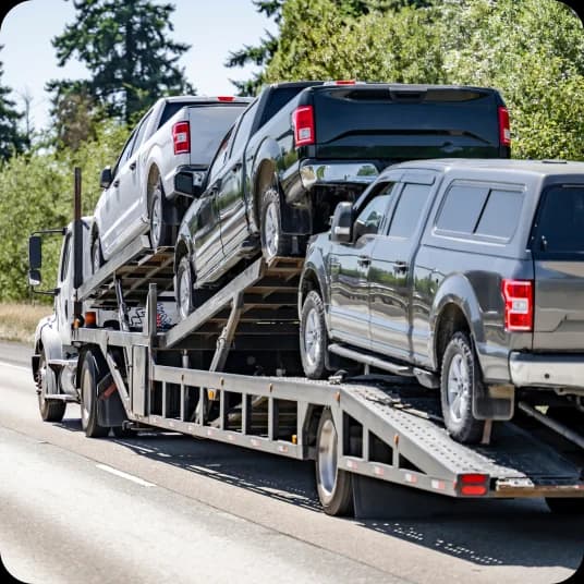 Three Cars being hauled via road