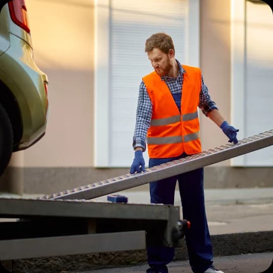 Worker preparing tow truck platform for car