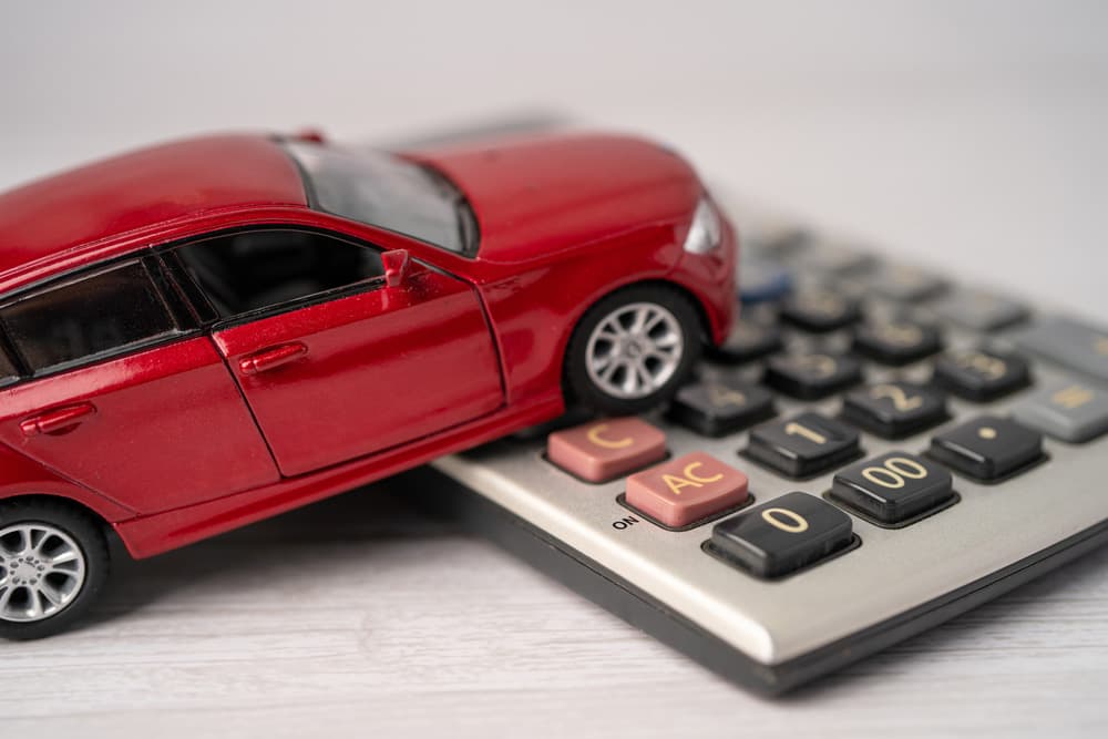Image related to blog title A red toy car on a calculator symbolizing the process of calculating auto shipping quotes and costs
