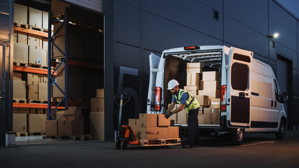 Image related to blog title Warehouse worker unloading boxes from a van, symbolizing packing a car for shipment.