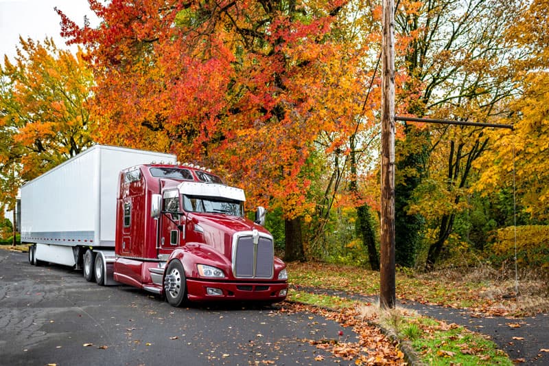 Image related to blog title Red box truck parked on a scenic road with vibrant autumn foliage in the background