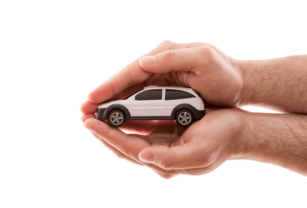 Image related to blog title Hands carefully holding a miniature car, symbolizing safe auto transport and secure vehicle shipping.