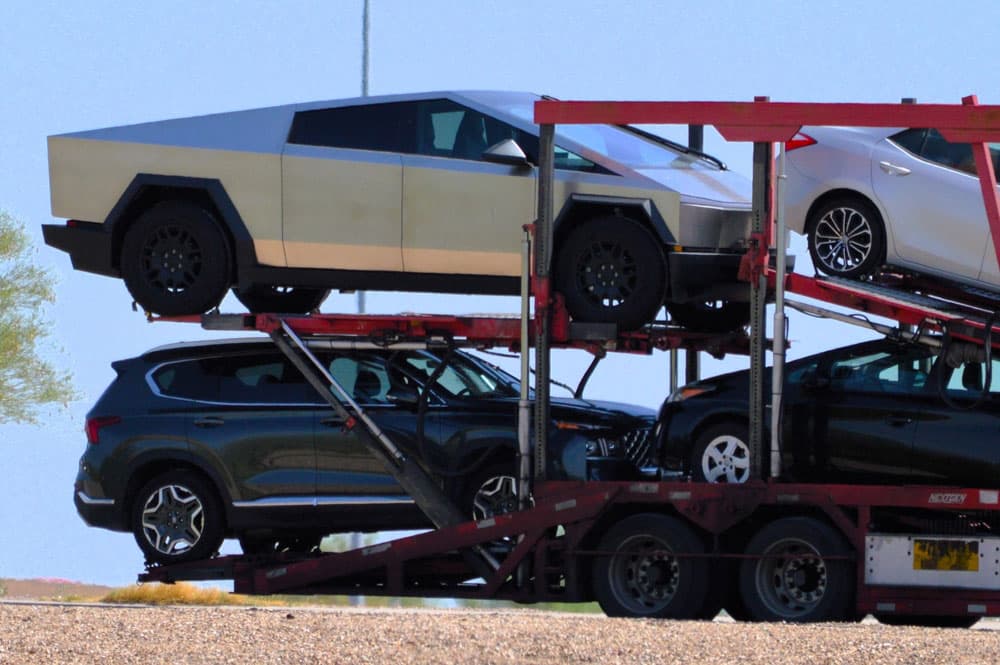 Image related to blog title Electric car transport on a multi-level trailer, featuring a futuristic design alongside other vehicles.