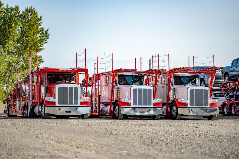 Image related to blog title Red car hauler trucks lined up in a lot, showcasing the efficiency of the car hauling business fleet.